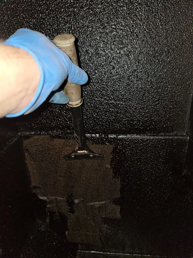 Technician scraping grease from kitchen exhaust duct in Rockford IL