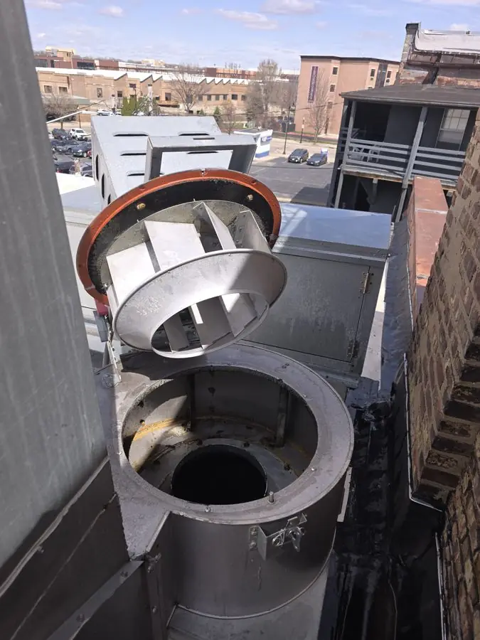 Rooftop kitchen exhaust fan tilted open on a hinge kit