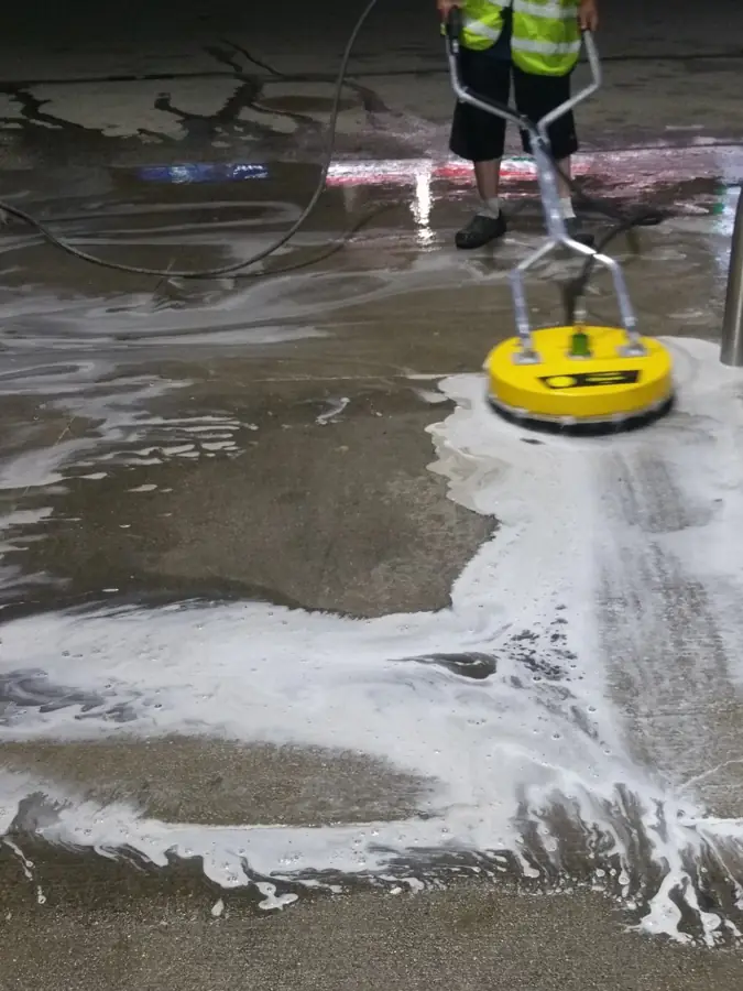 Technician surface cleaning a gas station concrete pad at night in Rockford IL
