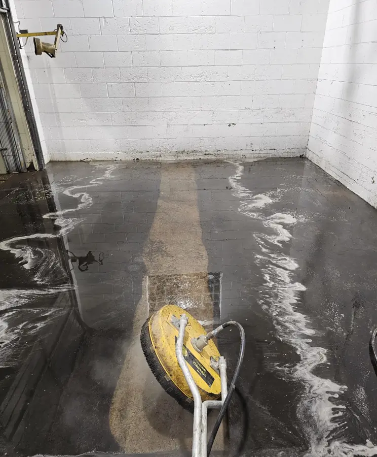 Warehouse concrete floor being cleaned, showing clean stripe through grime